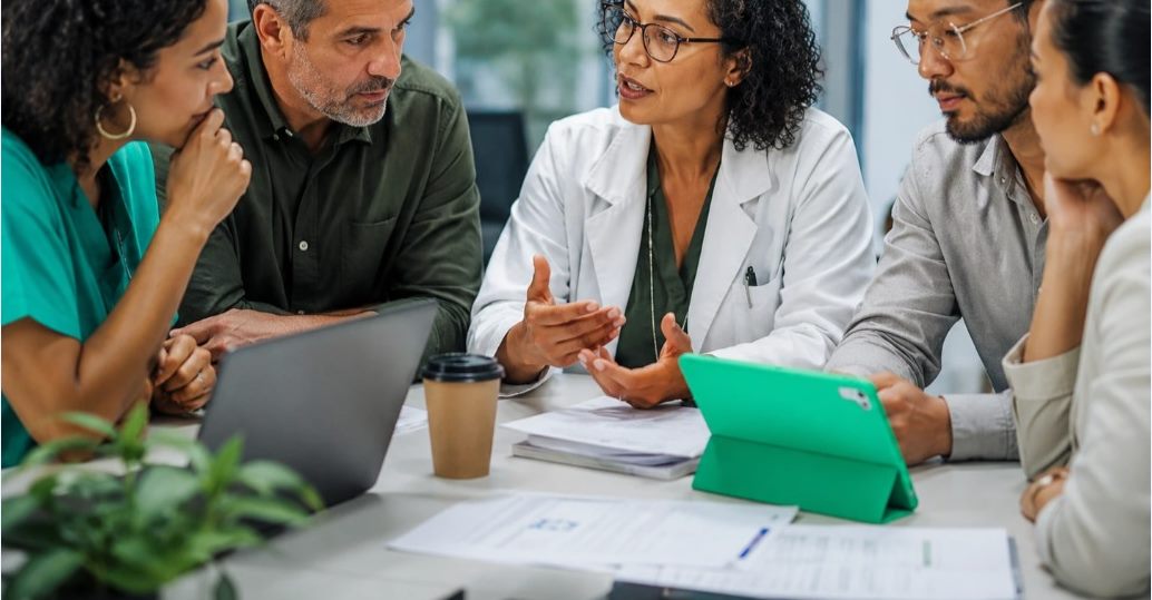 Médica conversando com pacientes ao redor de uma mesa